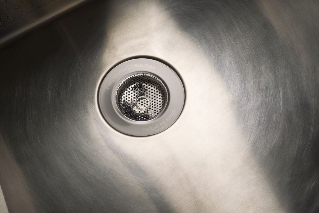 SemperScreen® permanent sink screen installed in a rental unit kitchen sink, holding food scraps above the drain opening