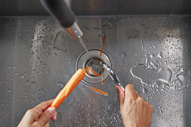Person peeling a carrot with a peeler under running water in a sink over the SemperScreen® permanent sink screen.